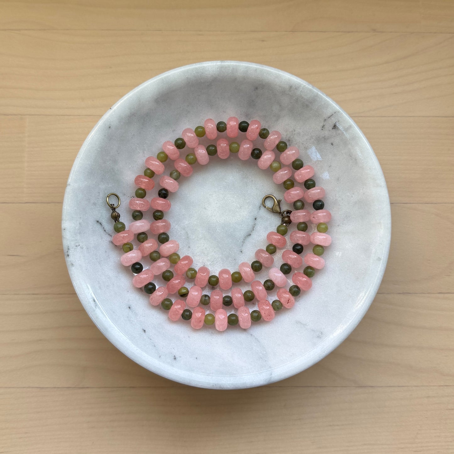 Beaded necklace on a marble dish with a wooden background