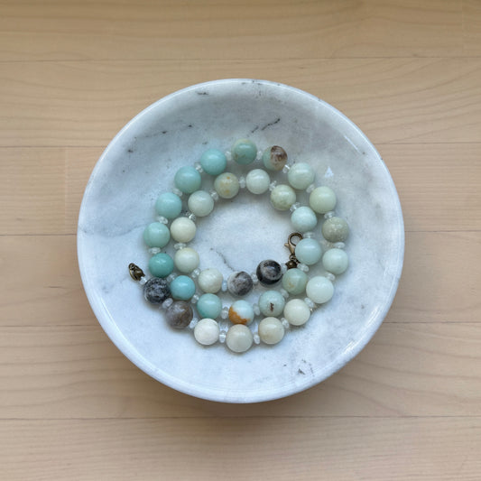 Beaded bracelet in a white dish on a wooden surface