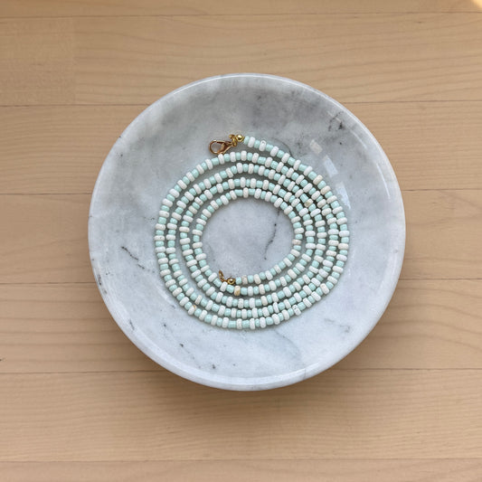 Marble dish with a necklace on a wooden surface